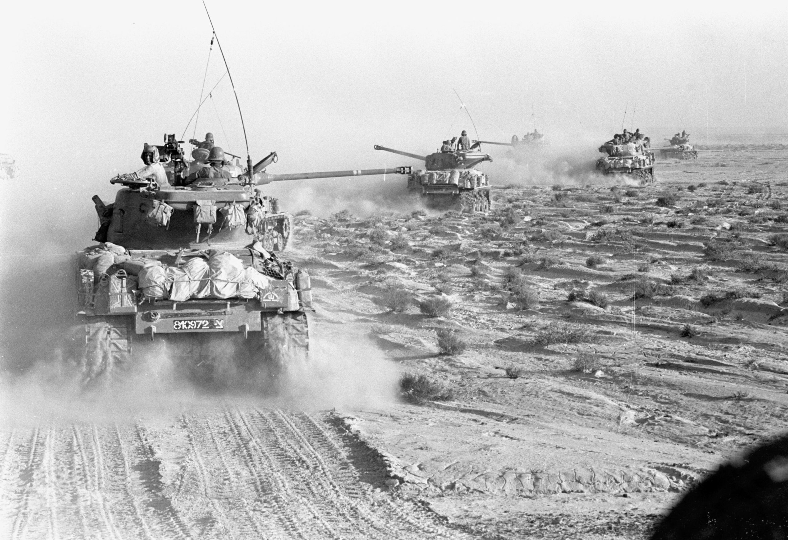Bilde av panservogner som kjører gjennom et ørkeområde.