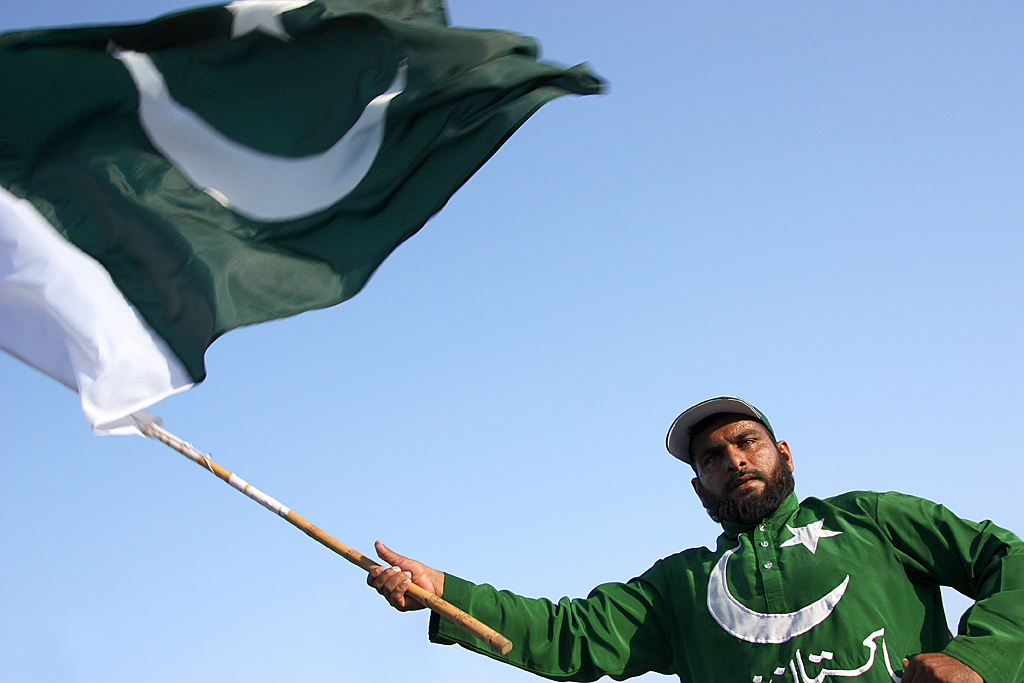 Mann holder det pakistanske flagget, og går med en genser med det pakistanske flagget