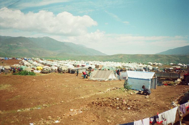 Flyktningleir, ute, blå himmel, sand på bakken og telt