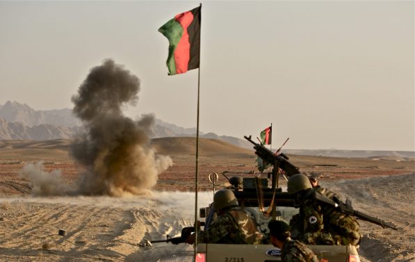 En veibombe sprenger i bakgrunnen, og forgrunnen ser vi afghansk militære.
