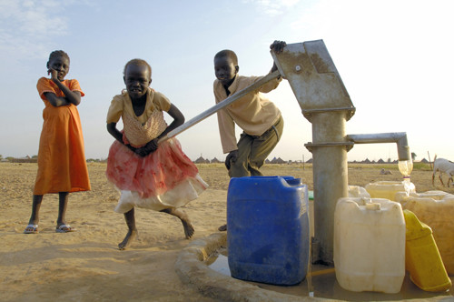 Barn pumper vann fra en brønn.