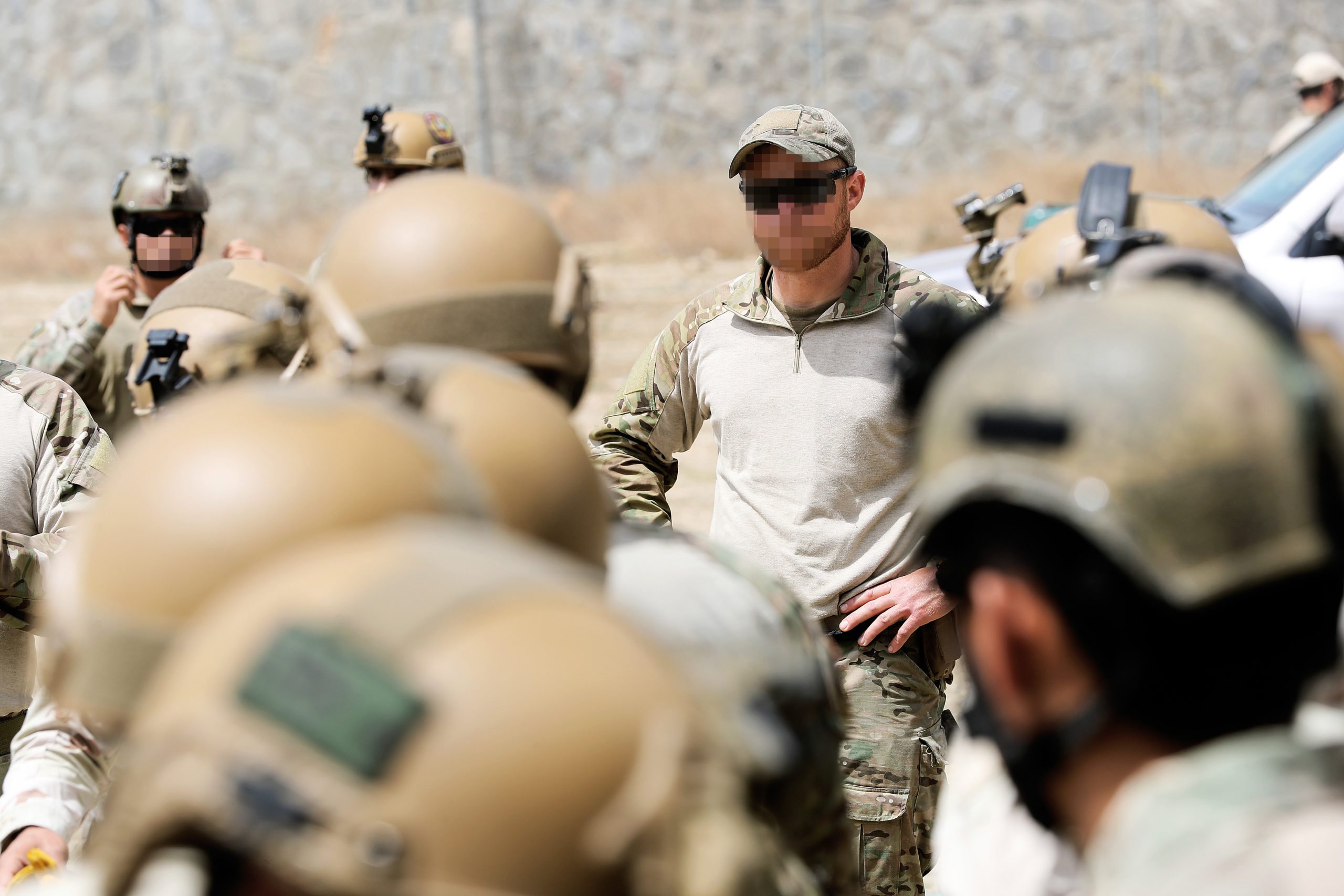 En rekke soldathjelmer i forgrunnen av bildet, i bakgrunnen ses en soldat kledd i treningsantrekk.