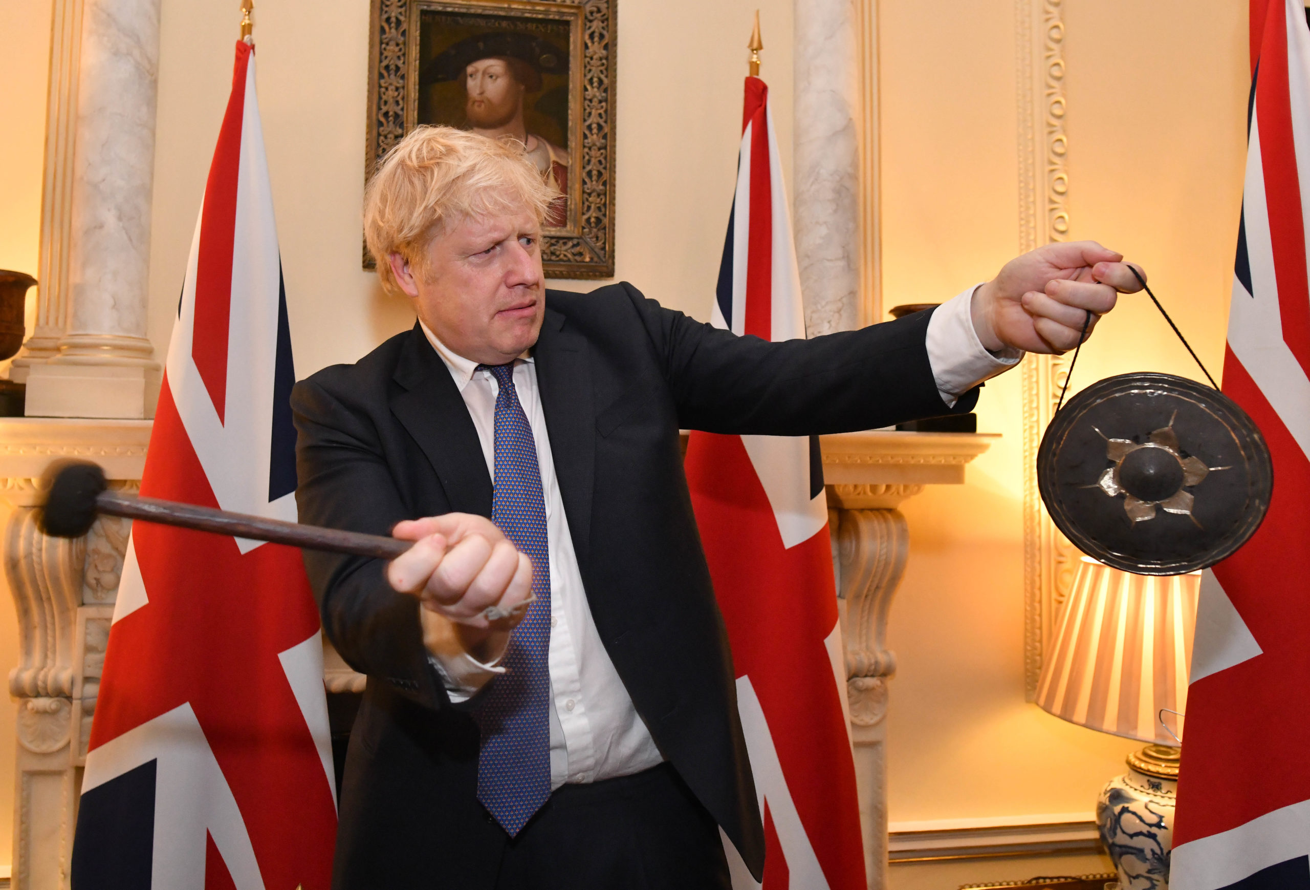 Boris Johnson slår på en gong med det britiske flagget i bakgrunnen.