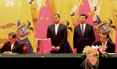 Ecuadors president Rafael Correa med kinas president Xi Jinping under statsbesøk i Kina. Bak dem er det flagg. To menn signerer, to menn står.