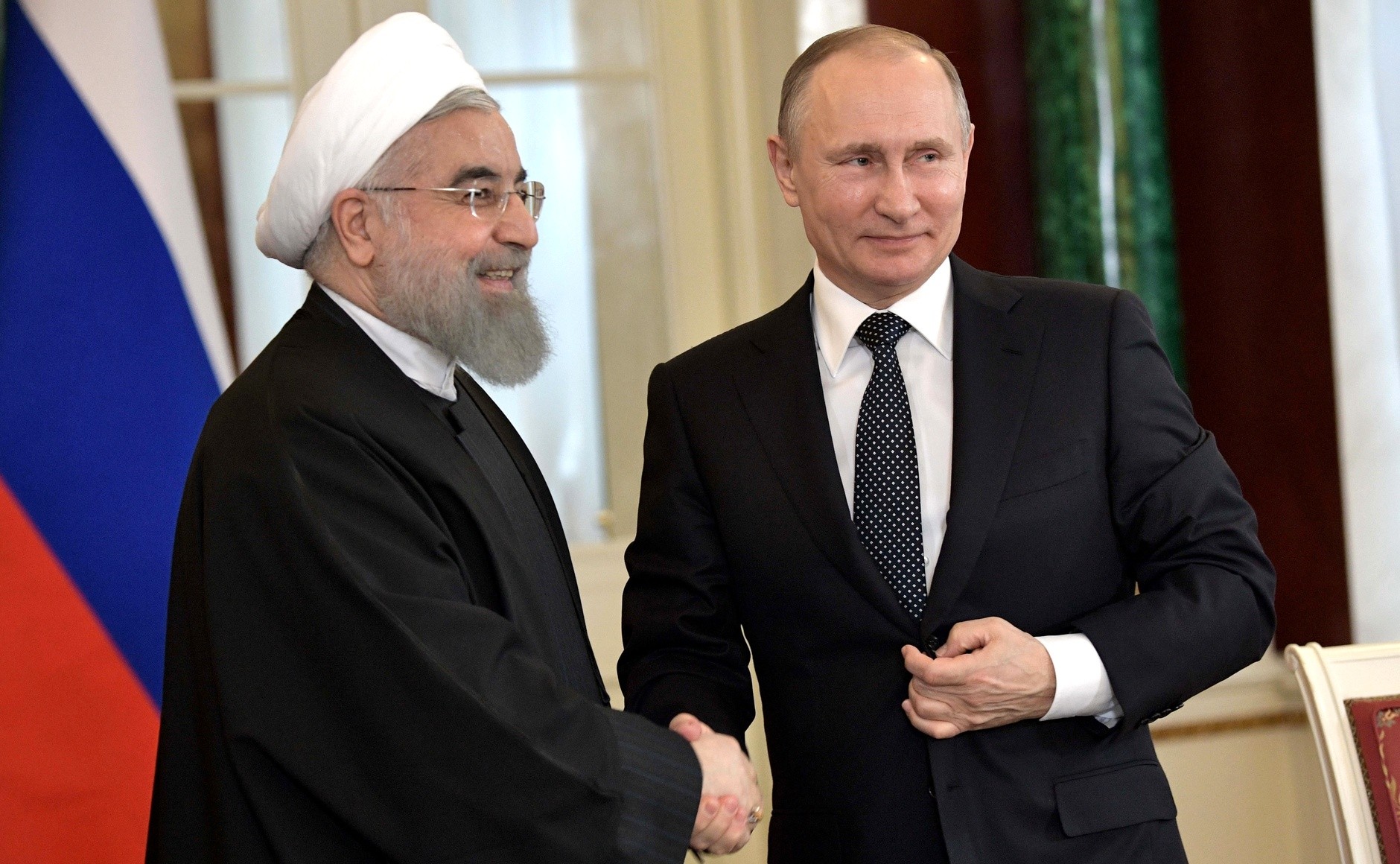 Russlands president Vladimir Putin og Irans president Hassan Rouhani tar hverandre i hånden.