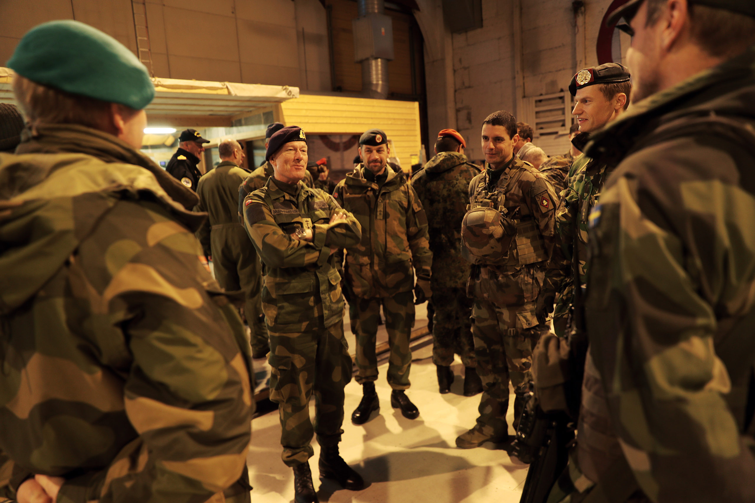 Mennesker kledd i militæruniform står i ring og snakker sammen.