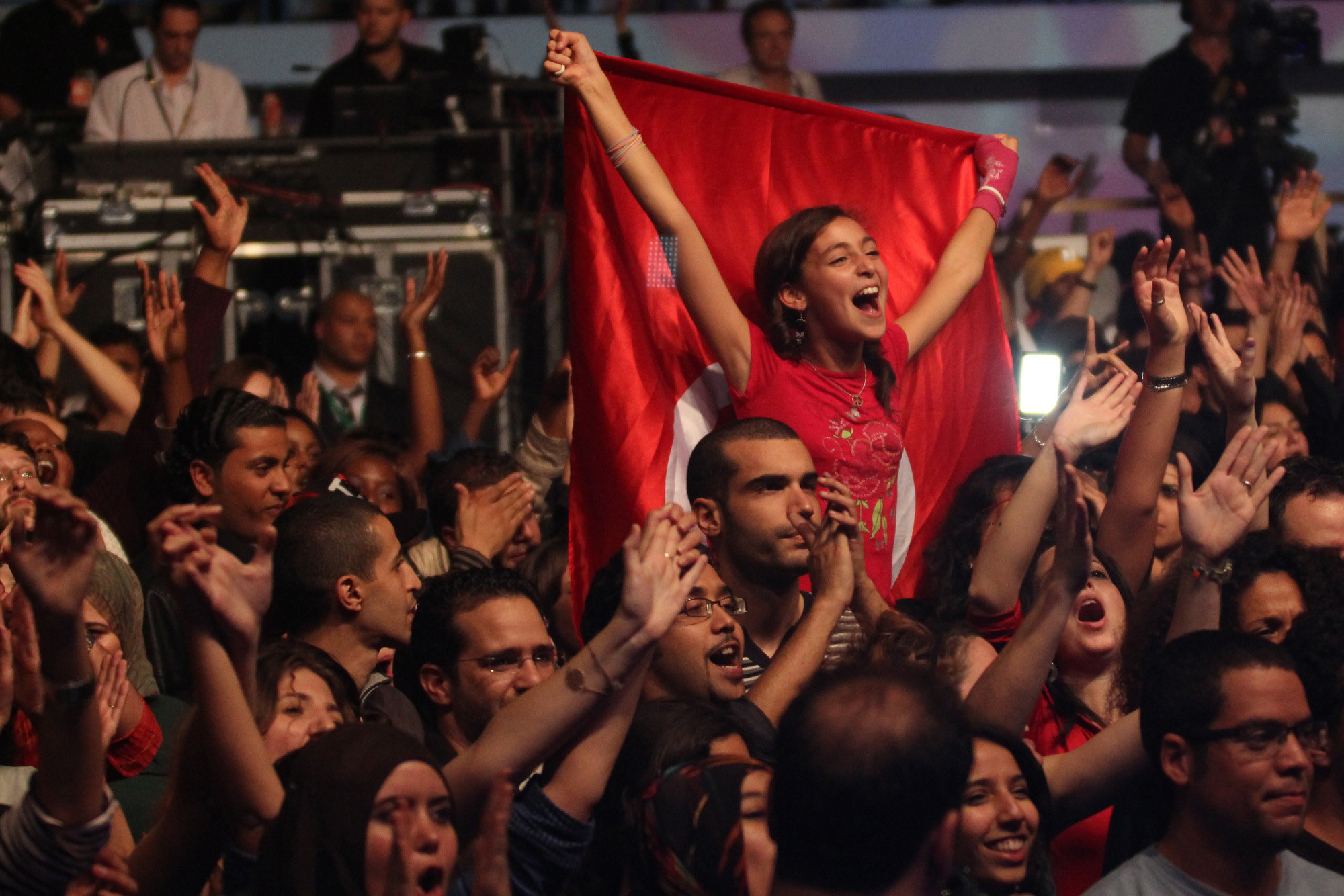 En stor folkemengde heier og ser glade ut. En dame veiver den tunisiske flagget bak seg.