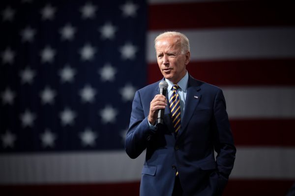 USAs president Joe Biden foran et amerikansk flagg med mikrofon i hånden