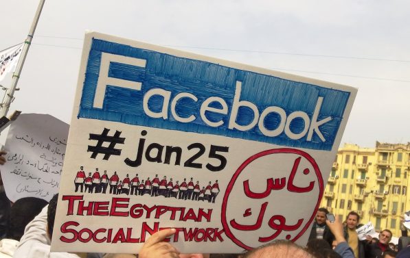 Demonstranter holder en plakat der det står Facebbok og #jan25