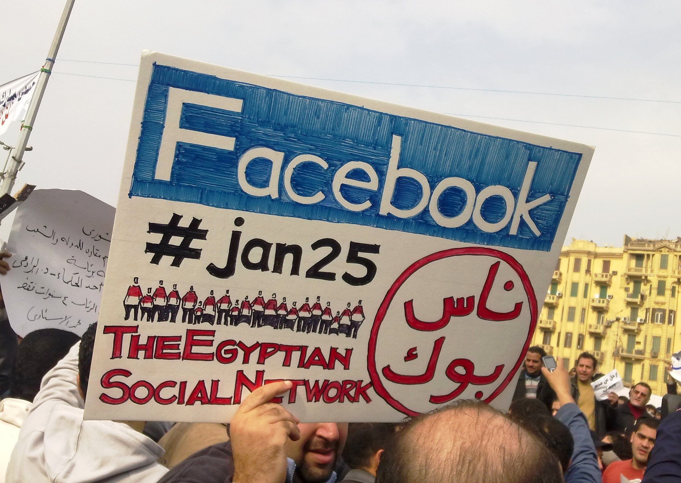 Demonstranter holder en plakat der det står Facebbok og #jan25