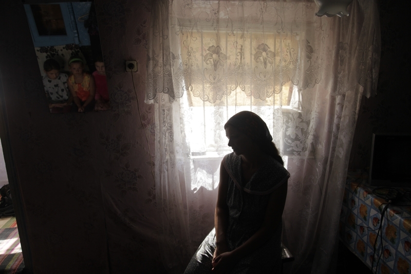 En kvinne sitter i skyggen av lyset fra vinduet.