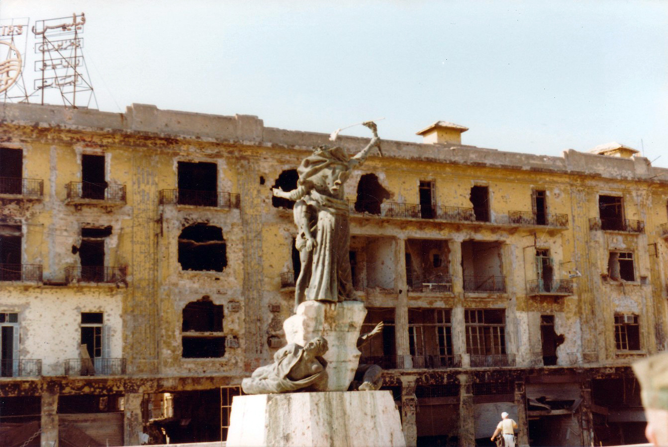En statue i midten av et torg som er tydelig skadet av eksplosjoner.