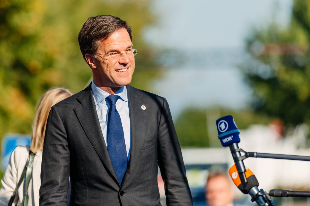 Mark Rutte smiler i sollyset mot en mikrofon.