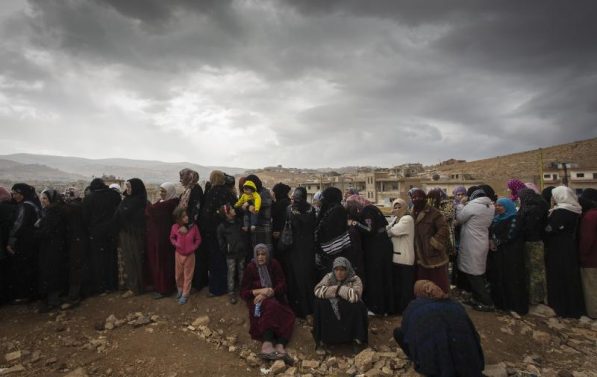 Syriske flyktninger står tett sammen i kø på grensen til Libanon.