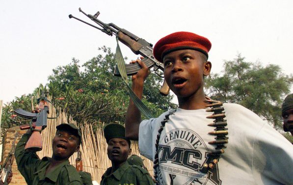 Tre barn fra en Uganda-støttet, kongolesisk opprørsgruppe synger og vifter med geværene sine.