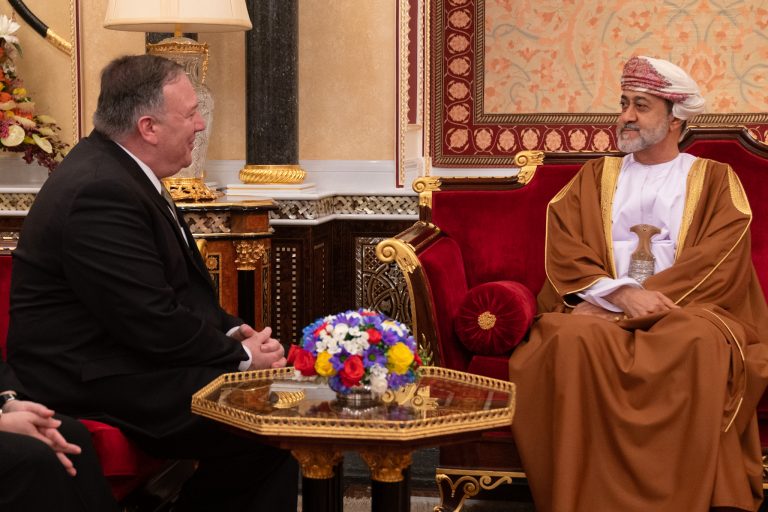 Utenriksminister Pompeo og Omans sultan sitter ved et bord og prater.