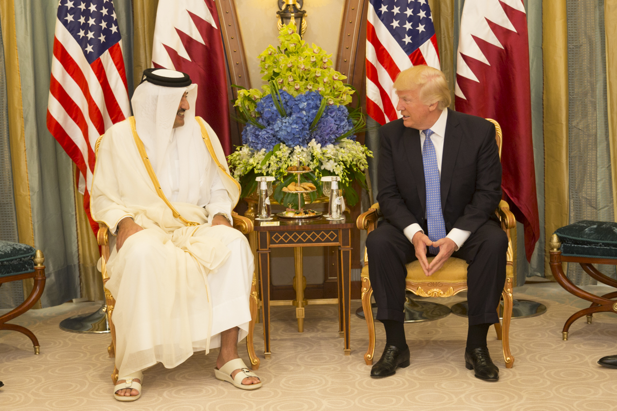 Qatars emir og President Trump prater sittende ved et lite bord.