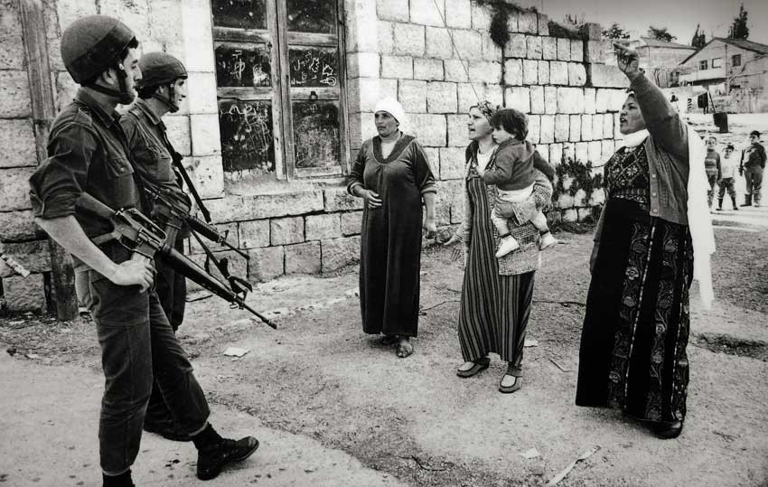 svart-hvitt bilde av tre kvinner som snakke til to soldater.