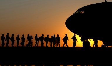 Soldater går inn i et fly i solnedgangen