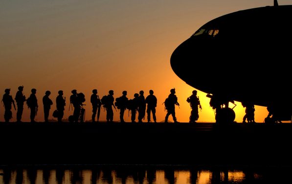 Soldater går inn i et fly i solnedgangen