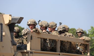 Soldater sitter på lasteplanet i en bil