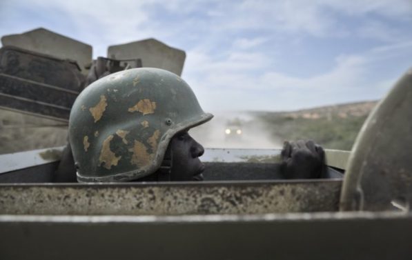 Soldat med hjelm på titter opp av luka på et pansret kjøretøy