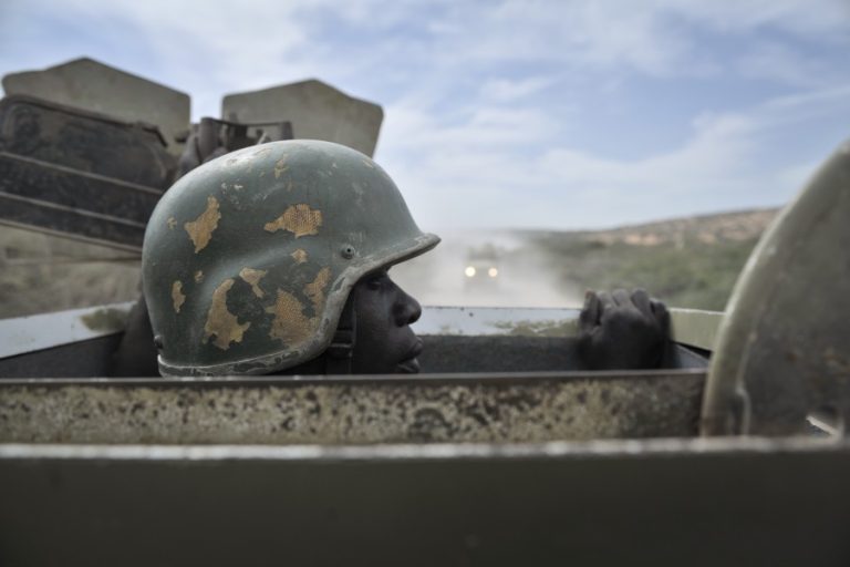 Soldat med hjelm på titter  opp av luka på et pansret kjøretøy