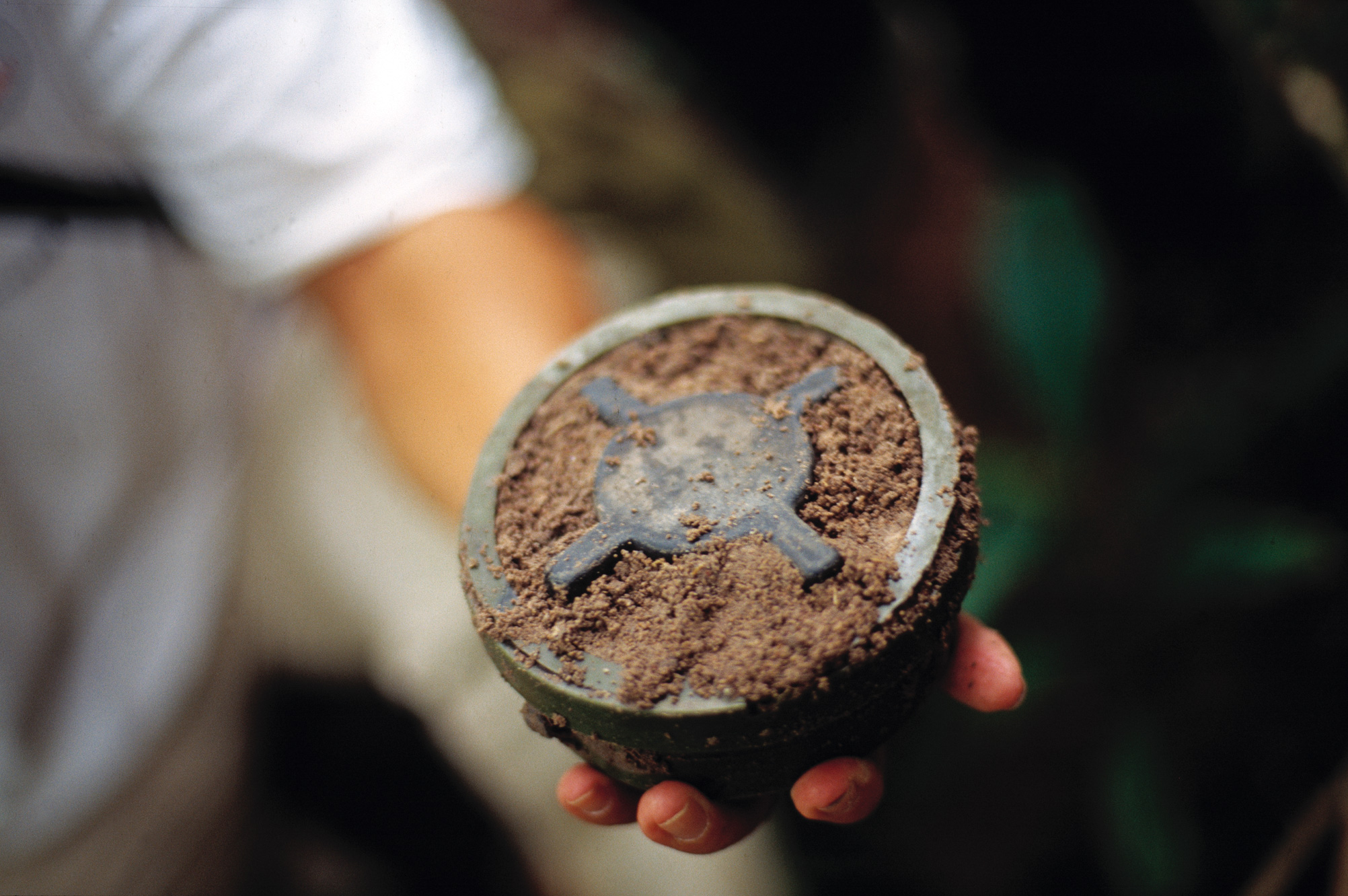 En hånd holder en oppgravd landmine.