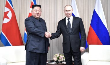 statslederne fra henholdsvis Nord-Korea og Russland håndhilser og ser i kamera