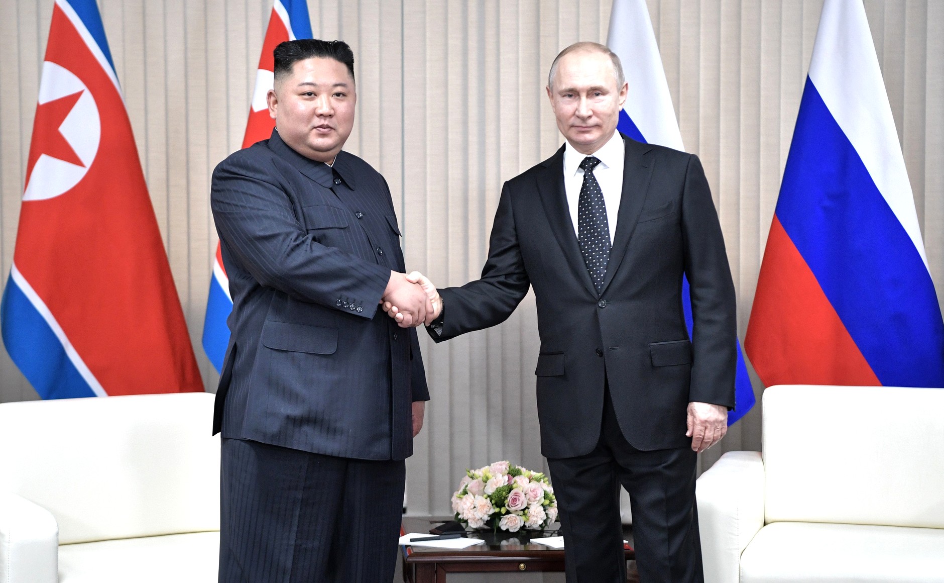 statslederne fra henholdsvis Nord-Korea og Russland håndhilser og ser i kamera