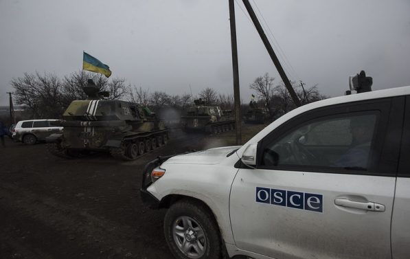 OSSE-bil står i nærheten av stridsvogner i Ukraina.