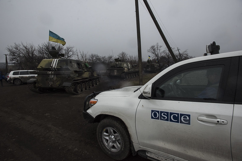 OSSE-bil står i nærheten av stridsvogner i Ukraina.