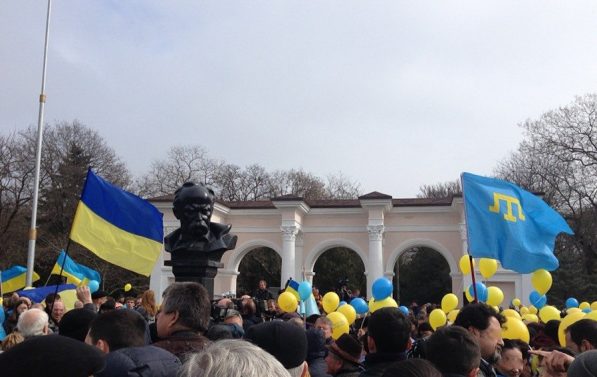Masse folk står tett i tett, det er ukrainske flagg og ballonger i gult og blått