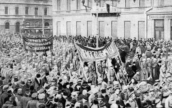 Svart-hvitt bilde en stor folkemengde. I sentrum av folkemengden en prosesjon med bannere skrevet på russisk.