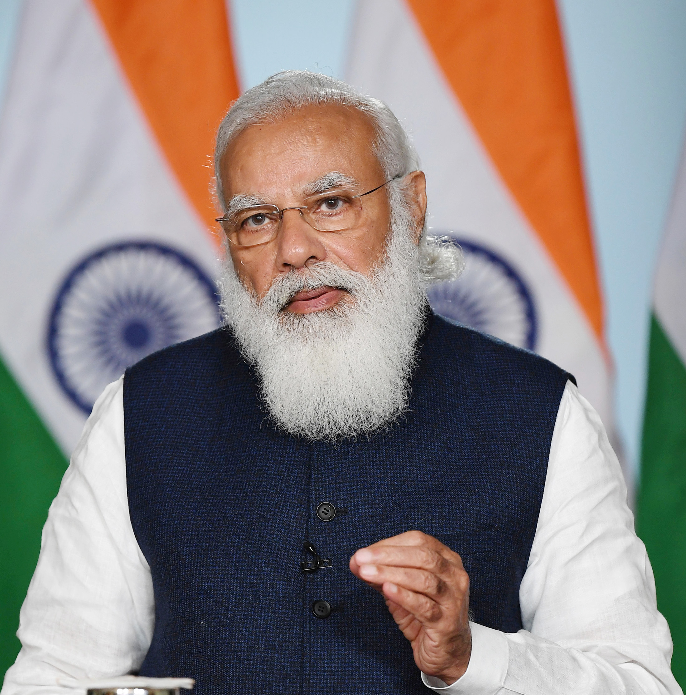 Portrett av statsminister Modi, bak ham står det indiske flagg, han har på seg skjorte og vest, og har et stort hvitt skjegg