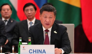Kinas statsleder snakker til en forsamling. Han sitter, og foran ham står det et skilt med "CHINA". Han har på seg dress.