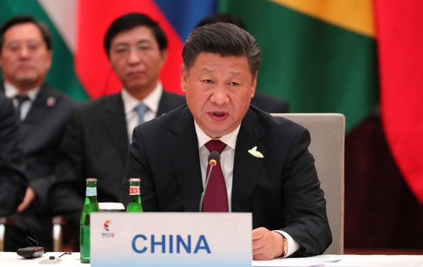 Kinas statsleder snakker til en forsamling. Han sitter, og foran ham står det et skilt med "CHINA". Han har på seg dress.