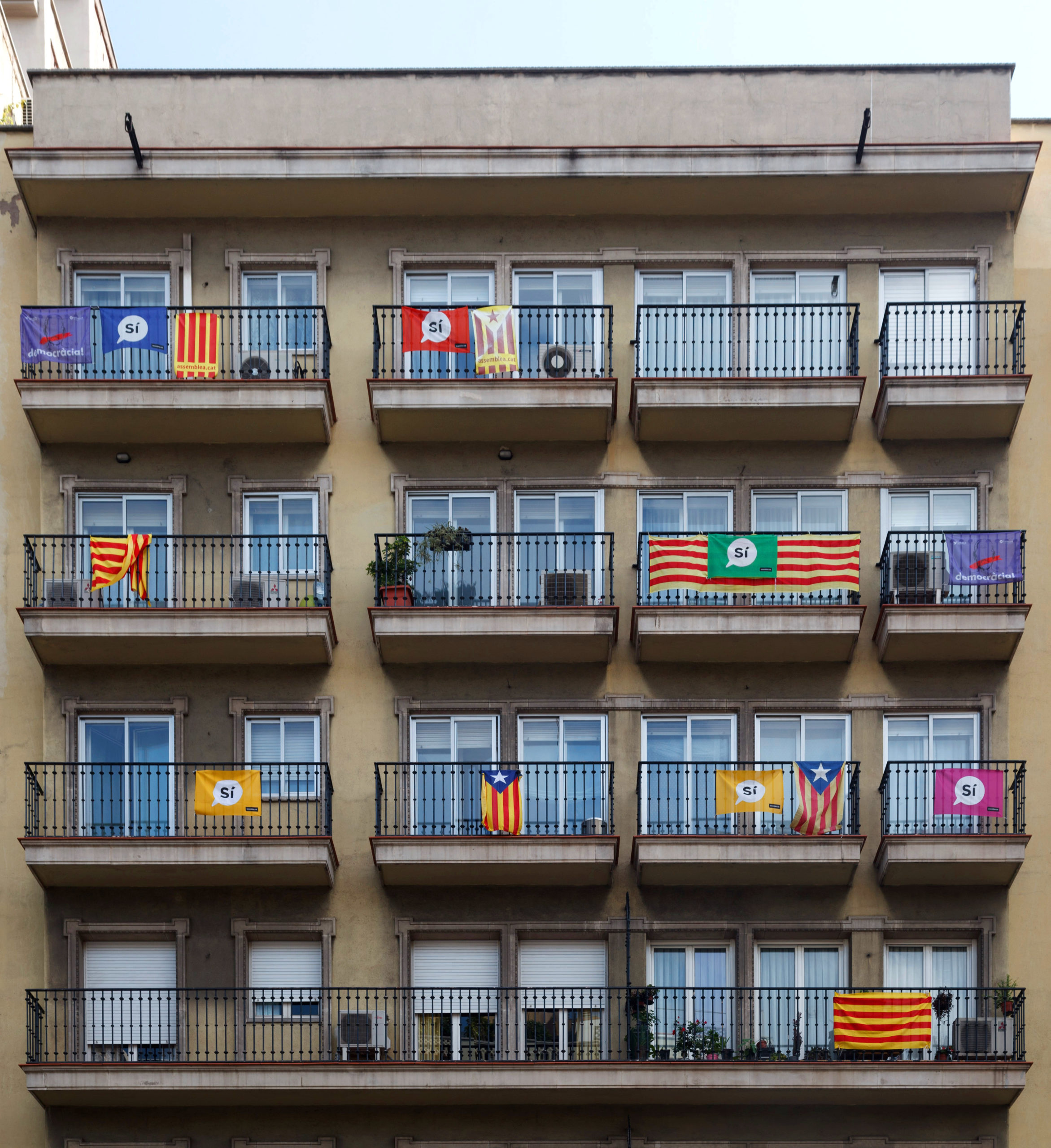 Boligblokk der ulike versjoner av det katalanske flagget henger på balkongen, mange har også hengt opp en "si" banner.
