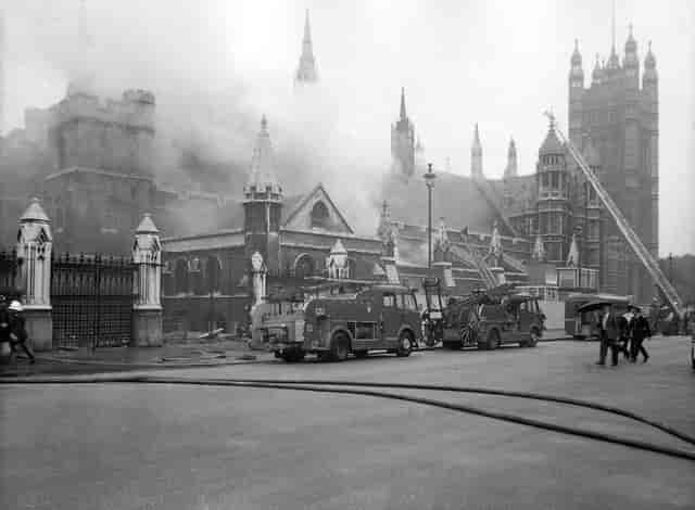 Svart-hvitt bilde av parlamentet i London der røyk siver ut.