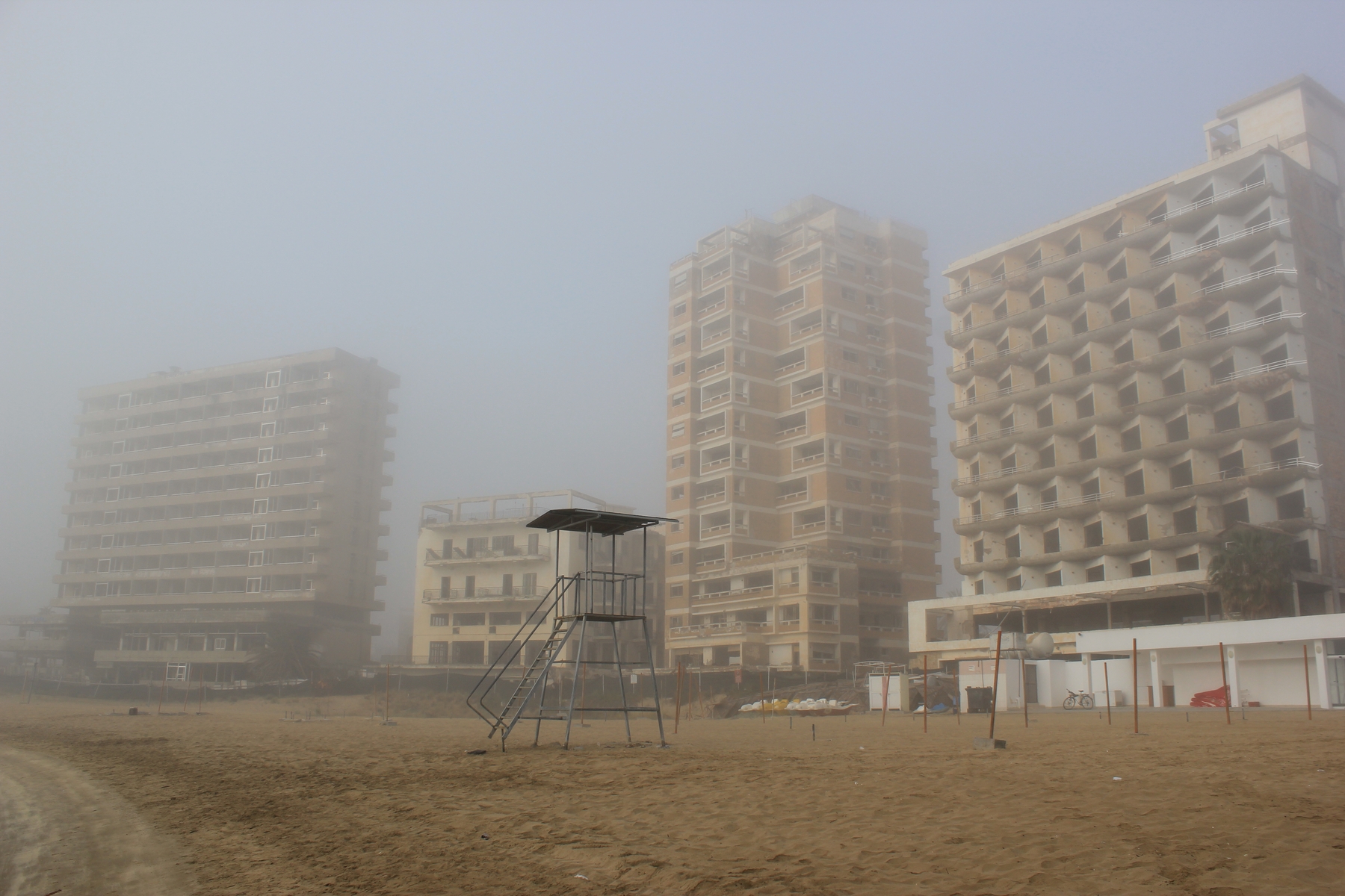 En tom strand med slitte bygninger i bakgrunnen