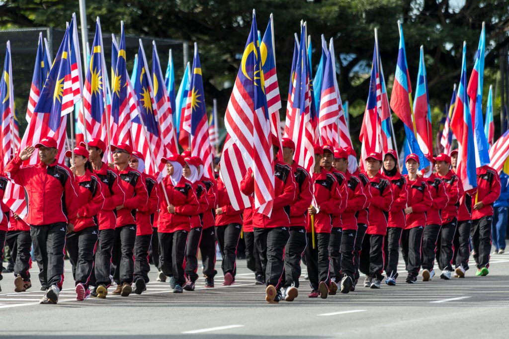 Rødkledde menn går i parade med det malaysiske flagget.