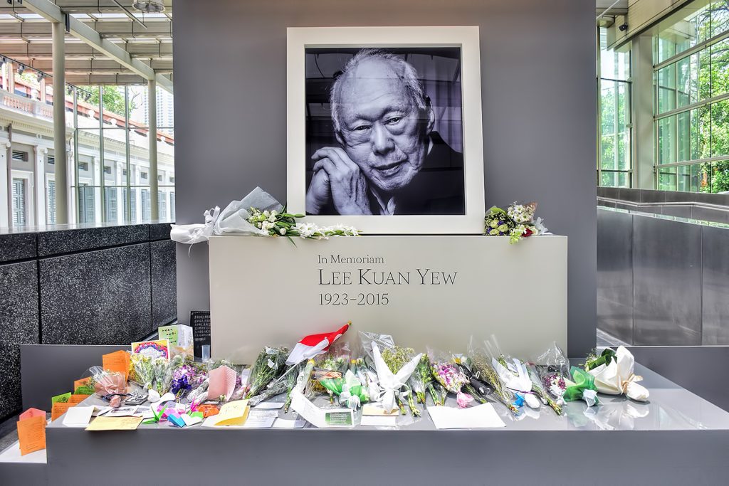 En grav hvor Lee Kuan Yews navn og bilde står. Foran ligger masse blomster.