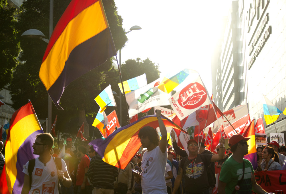 Demonstranter med spanske flagg og andre bannere går gjennom en gate