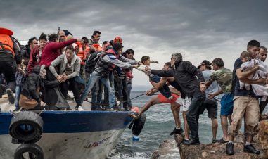 Mennesker er på vei over fra en overfylt åpen båte til land.