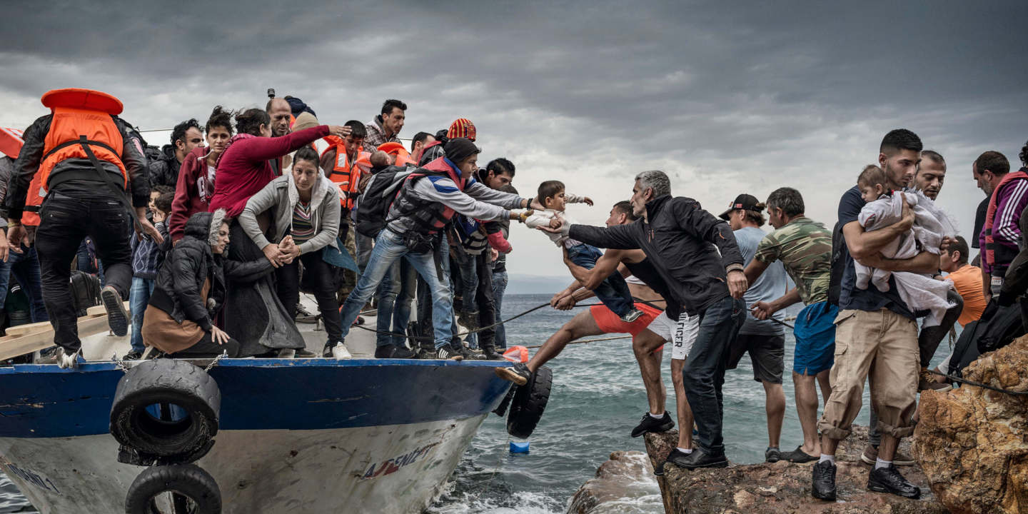 Mennesker er på vei over fra en overfylt åpen båte til land.