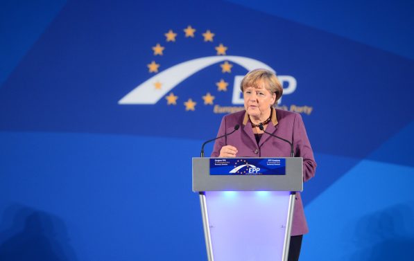 Angela Merkel taler fra en talerstoler. I bakgrunnen ser men EU-stjernene.