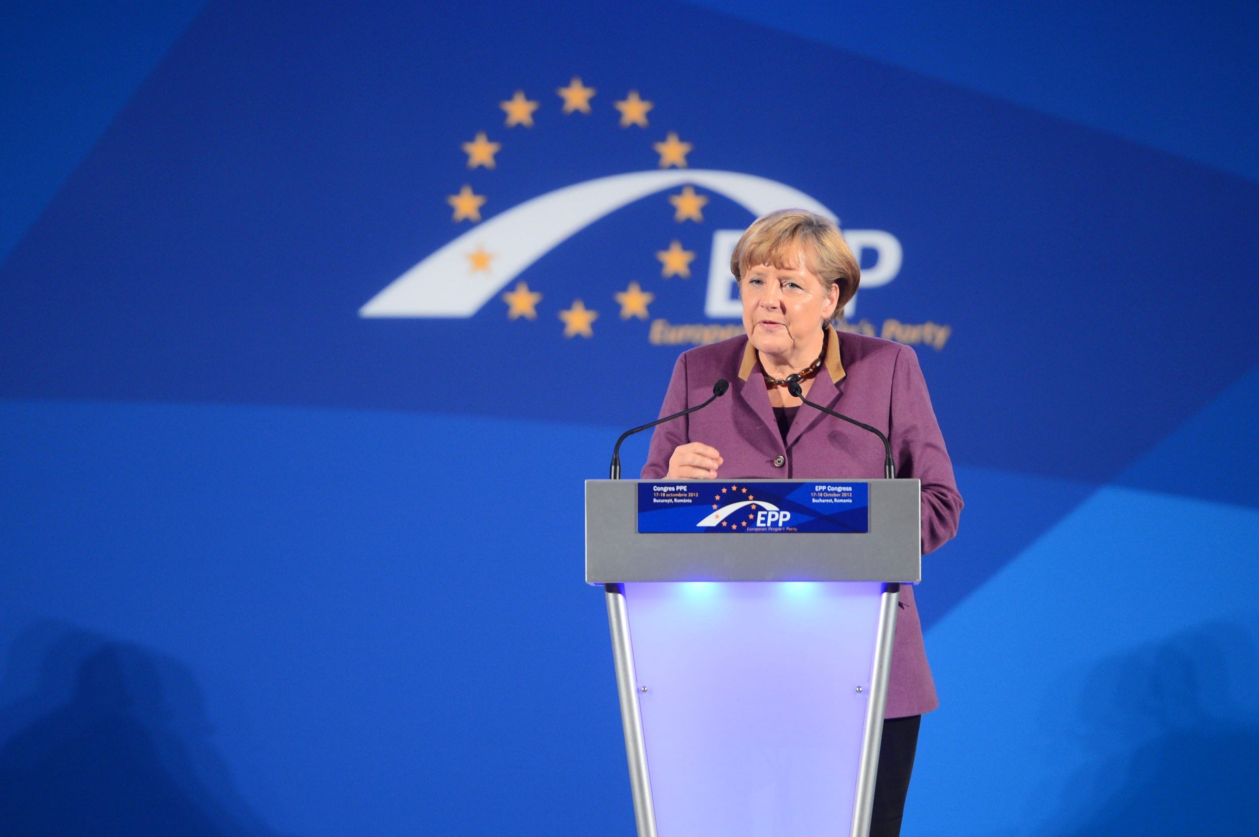 Angela Merkel taler fra en talerstoler. I bakgrunnen ser men EU-stjernene. 