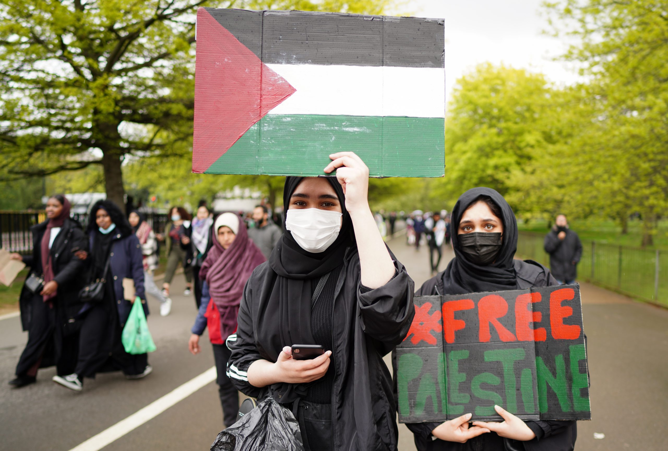 Folk demonstrerer med palestinske flagg og plakater hvor det står "fri Palestina". 
