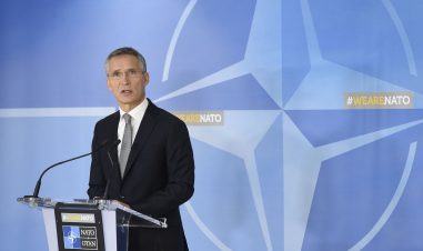 Jens Stoltenberg ved en talestol med NATOs logo i bakgrunnen