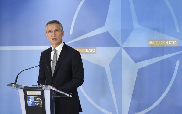 Jens Stoltenberg ved en talestol med NATOs logo i bakgrunnen